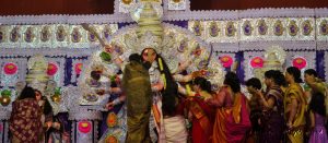 Women apply sindoor to Goddess Durga