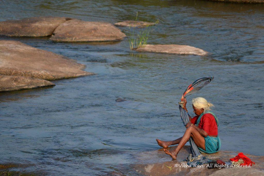 Indian woman washing clothes by the riverside - PixelVoyages